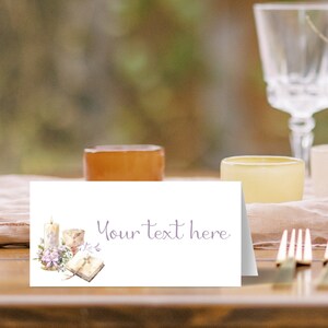 May include: White place card with a watercolor illustration of a candle, a chalice, and a book with a cross on it. The text "Your text here" is written in purple script.