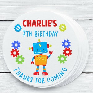 May include: Round favor tags with a blue robot with yellow and orange details, surrounded by colorful gears. The text reads "Charlie's 7th Birthday Thanks for Coming".