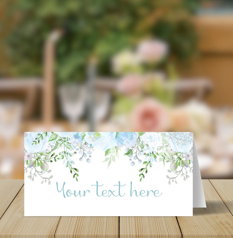 May include: A white place card with a blue watercolour floral design. The text "Your text here" is printed in blue at the bottom of the card.