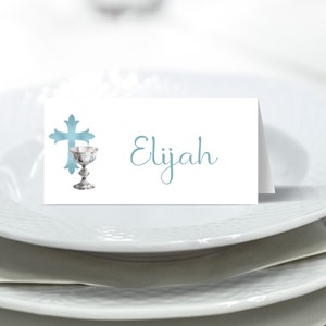 May include: A white place card with a blue cross and chalice design. The name Elijah is written in blue cursive script.