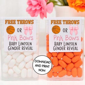 May include: Two clear plastic containers filled with candy. One container has white candy and the other has orange candy. Both containers have labels that say "Free Throws or Pink Bows Baby Lincoln Gender Reveal".