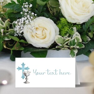 May include: A white card with a blue cross and chalice design. The text "Your text here" is written in blue cursive script.