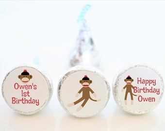 Puede incluir: Tres caramelos redondos de chocolate envueltos en papel de aluminio plateado con etiquetas personalizadas que muestran un mono de dibujos animados con un sombrero rojo. Las etiquetas dicen "Owen's 1st Birthday" y "Happy Birthday Owen".