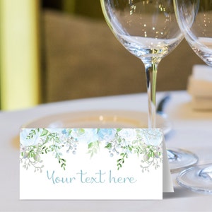 May include: White place card with a blue floral design and the text "Your text here".