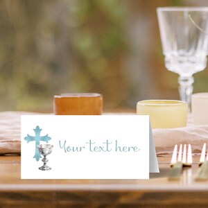 May include: A white place card with a blue cross and chalice design. The text "Your text here" is printed in blue on the card.