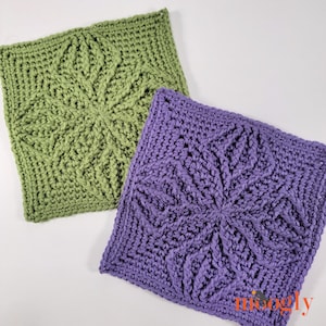 Puede incluir: Dos motivos cuadrados de ganchillo con un patrón central de estrella y textura en relieve. Un cuadrado es de color verde salvia y el otro es de color lavanda. Ambas piezas están hechas de hilo y muestran un diseño geométrico repetitivo.