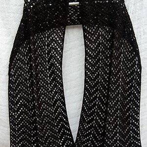 May include: A black chevron lace wrap, suspended from a white hanger. The wrap features an open, patterned weave and a scalloped border. The text "chevron lace wrap on mooglyblog.com" is displayed at the bottom.