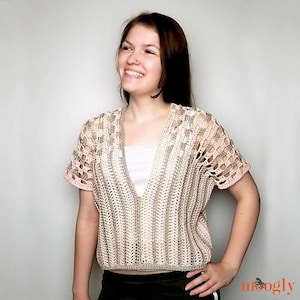 May include: A crocheted top with a V-neck and short sleeves. The top is made with a combination of pink, beige, and white yarn. The top is cropped and has a relaxed fit.