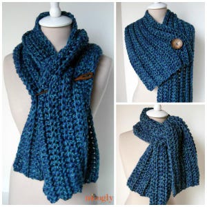 Peut inclure: Écharpe au crochet bleue faite à la main avec une fermeture à bouton. L'écharpe est présentée sur un mannequin et présente un motif de point texturé. L'écharpe est un mélange de couleurs bleues et turquoise.