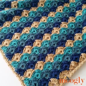 May include: A crocheted blanket with a geometric pattern in shades of blue, teal, and brown.