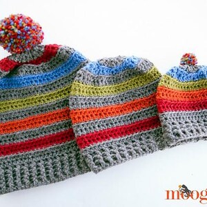 May include: Three handmade crochet hats in varying sizes, featuring horizontal stripes in gray, red, orange, yellow, blue, and a multicolored pom-pom. The hats are displayed on a white background, showcasing the colorful, textured design.