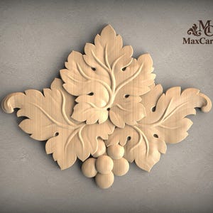 May include: A light-colored wooden carving featuring a cluster of grape leaves and a small bunch of grapes at the bottom. The design includes intricate veining on the leaves and rounded shapes for the fruit. The text MaxCarving is visible.