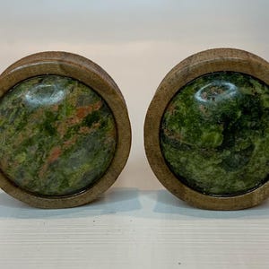 May include: Pair of round wooden ear gauges with green and brown marbled stone inserts.