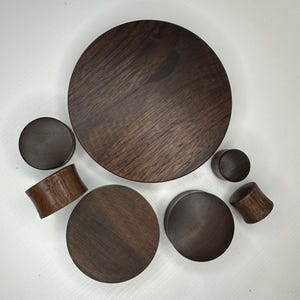 Peut inclure: Un ensemble de six jauges d'oreille en bois de différentes tailles, en bois de noyer brun foncé. Les jauges sont rondes et ont une finition lisse et polie.