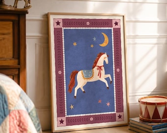 May include: A framed rectangular wall art print featuring a cream-coloured horse with a red mane and tail, wearing a blue saddle. The horse is set against a blue background with a yellow crescent moon and stars, bordered by a dark pink frame.