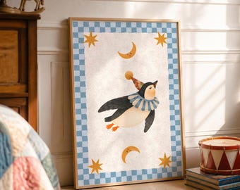 May include: A framed wall art print featuring a central illustration of a penguin wearing a ruffled collar and a party hat. The penguin is surrounded by four yellow stars and two crescent moons on a cream background with a blue checkered border.