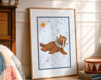 May include: A framed wall art print featuring a brown walrus wearing a blue and white striped ruffled collar and a small red party hat. The walrus is set against a light blue background with a yellow star and small blue star accents.