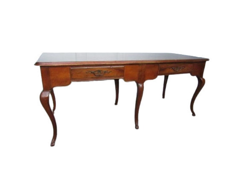 May include: A long, rectangular wooden table with three drawers and cabriole legs. The table is made of a dark wood with a rich brown finish.