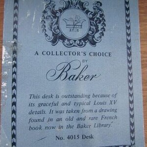 May include: A blue and white card with a decorative crest and the text "A Collector's Choice by Baker". The text below the crest reads "This desk is outstanding because of its graceful and typical Louis XV details. It was taken from a drawing found in an old and rare French book now in the Baker Library." The card also includes the text "No. 4015 Desk".