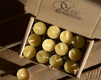 May include: A box of 12 small, round, yellow beeswax tea lights in a cardboard box with the text "Bee from hive to home BEESWAX ALCHEMY".