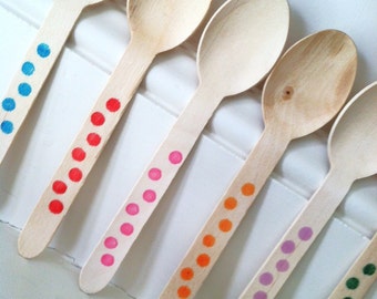 May include: Five wooden spoons with colorful polka dot designs. The spoons are arranged in a row, with the blue polka dot spoon at the top and the green polka dot spoon at the bottom.