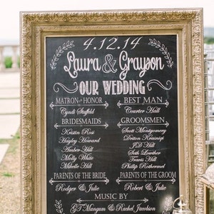 Könnte beinhalten: Eine schwarze Tafel mit goldenem Rahmen listet die Hochzeitsgesellschaft für die Hochzeit von Laura & Grayson am 4.12.14 auf. Die Tafel listet die Trauzeugin, die Brautjungfern, den Trauzeugen, die  Brautjungfern, die Eltern der Braut, die Eltern des Bräutigams, die Musik und den Standesbeamten auf.