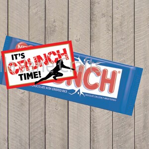 May include: A red and white sticker with the text "It's Crunch Time!" and a silhouette of a person doing a karate kick. The sticker is placed on top of a blue and red chocolate bar wrapper with the text "Crunch" on it.