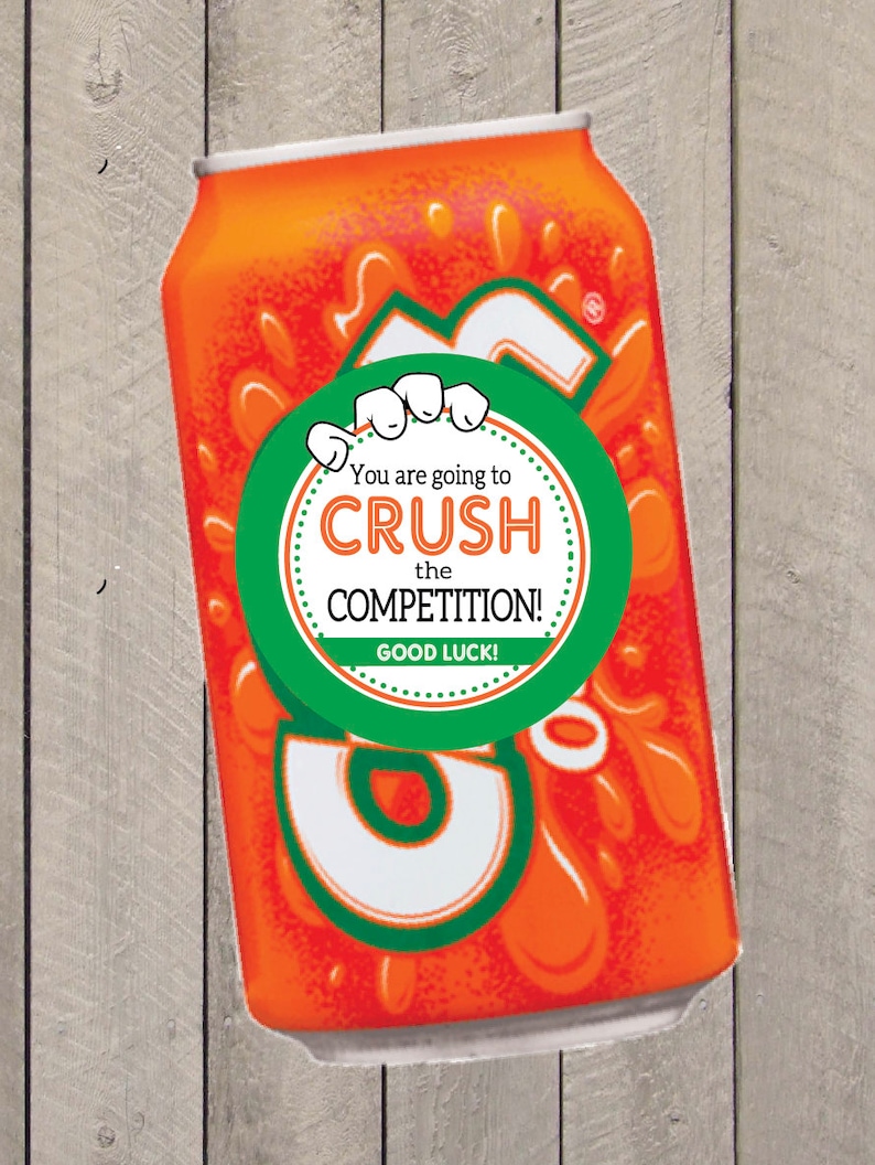 K&ouml;nnte beinhalten: Eine orangefarbene und gr&uuml;ne Dose mit einem wei&szlig;en runden Aufkleber, auf dem steht "You are going to CRUSH the COMPETITION! GOOD LUCK!"