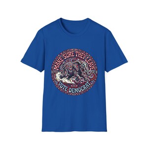 Op de afbeelding: Koningsblauw T-shirt met een cirkelvormige afbeelding. De afbeelding toont een olifant en de tekst "MAKE SURE THEY LEAVE" en "VOTE DEMOCRAT". De olifant is rood, wit en blauw. Het T-shirt heeft een klassieke ronde hals.