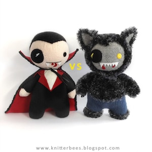 Puede incluir: Un conjunto de juguetes de peluche de punto de un vampiro y un hombre lobo. El vampir lleva un traje negro con una capa roja y tiene la lengua roja fuera. El hombre lobo lleva pantalones vaqueros azules y tiene un abrigo de piel gris. El texto "VS" está impreso entre los dos juguetes.