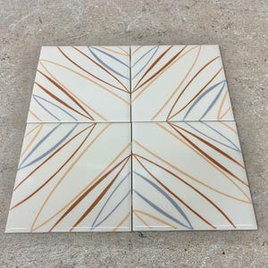 May include: Four square ceramic tiles with a white background and a pattern of brown and gray lines. The lines are curved and create a geometric design.