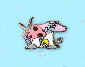 May include: A pink and white mushroom with a red cap and black spots, surrounded by green leaves and a small snail. The mushroom is sitting on a small rock.