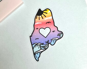 May include: A sticker of the state of Maine with a sunset, waves, and a heart in the middle. The sticker is on a light blue background.