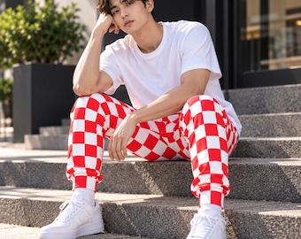 May include: A plain white short-sleeved crew neck t-shirt paired with red and white checkered jogger pants featuring elastic cuffs at the ankles, worn with solid white low-top sneakers and white socks, creating a casual outfit.