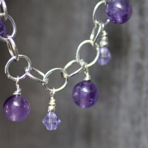 May include: A silver chain bracelet with multiple dangling amethyst beads and a single crystal charm.