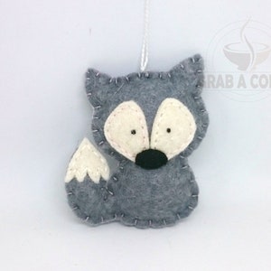 May include: A gray felt fox ornament with white felt accents on the ears and tail. The fox has black felt eyes and a black nose.