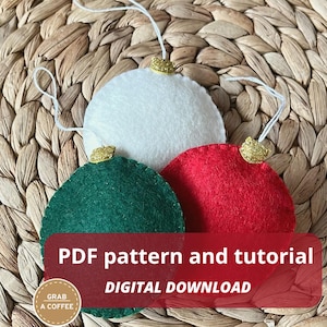May include: Three round felt ornaments in white, dark green, and red, each topped with a gold glitter cap and a white hanging string. The image includes the text: PDF pattern and tutorial DIGITAL DOWNLOAD and GRAB A COFFEE.