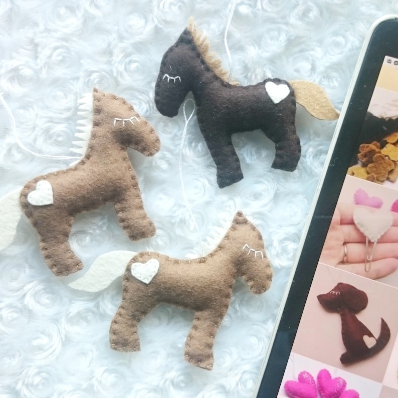 May include: Three felt horse ornaments with white felt hearts. Two are brown and one is black.