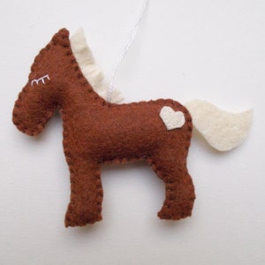 May include: A brown felt horse ornament with a white felt mane, tail, and heart on its back.