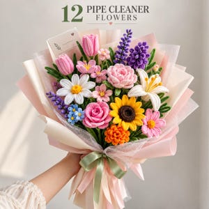 May include: A bouquet of 12 pipe cleaner flowers featuring a variety of colorful blooms including pink tulips, a yellow sunflower, a white lily, and purple lavender. The arrangement is wrapped in light pink paper with a green ribbon.