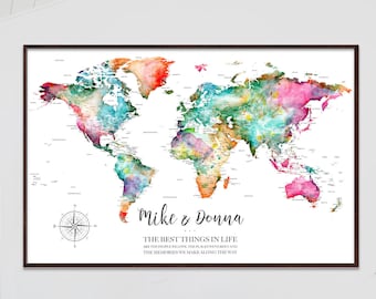 May include: A watercolor world map with a colorful design. The map is framed and has a compass in the bottom left corner. The text "Mike & Donna" is written in cursive at the bottom of the map, along with the quote "The best things in life are the people we love, the places we've been, and the memories we make along the way."