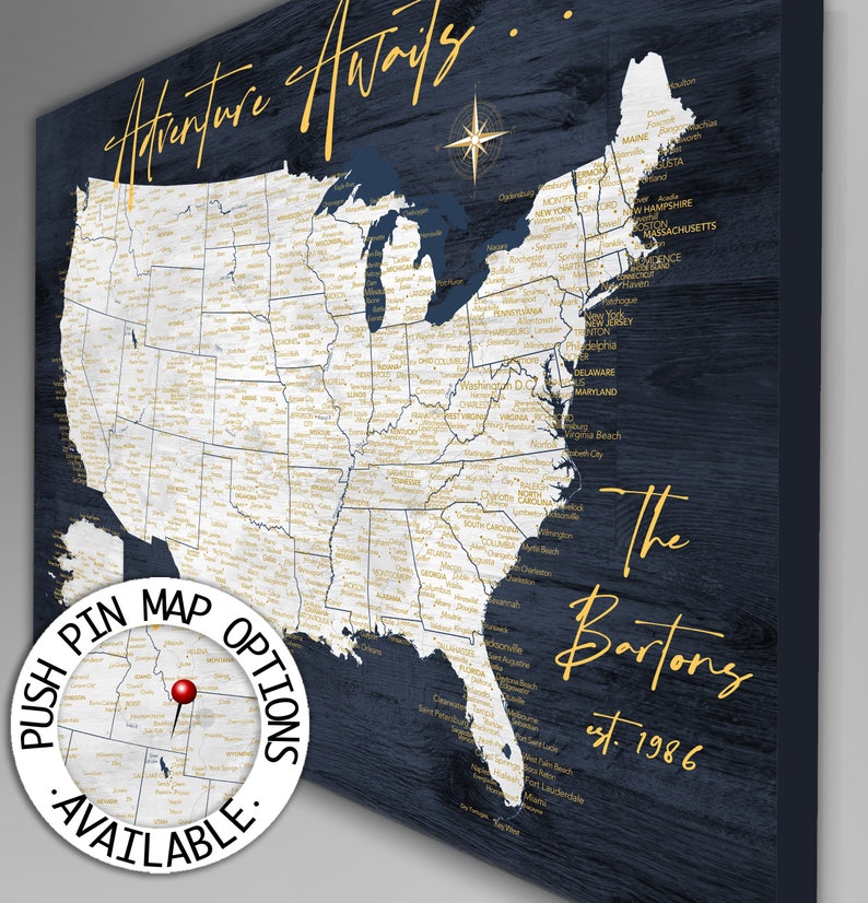 May include: A blue and white map of the United States with gold lettering. The map is on a dark blue wood background. The text on the map says "Adventure Awaits... The Bartons est. 1986". There is a small circle in the lower left corner that says "Push Pin Map Options Available."
