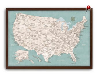 May include: Framed map of the United States with a teal background and a dark brown wooden frame. The map is detailed with state names and city labels. A red push pin is placed on the map.