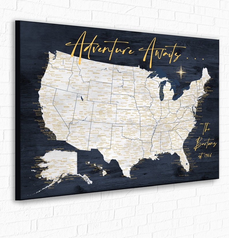 May include: A blue and white map of the United States with the text "Adventure Awaits..." and "The Bartons est. 1996" printed on it. The map is on a canvas with a wood grain texture.