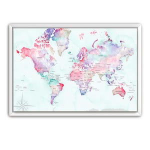 May include: A framed world map with a watercolor design. The map features a light blue background with continents in shades of pink, purple, and teal. Country names are labeled in a dark font. A compass rose is in the lower left corner.
