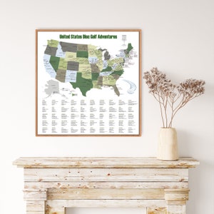 May include: A framed map titled "United States Disc Golf Adventures" depicts the U.S. with states in shades of green and gray. The map includes a disc golf basket graphic and a legend with text. The frame is a light brown color.
