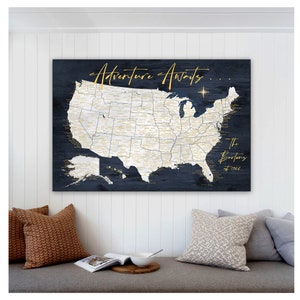 May include: A dark blue wooden map of the United States with gold lettering. The map is titled "Adventure Awaits..." and has a gold star in the upper right corner. The text "The Bartons est 1986" is in the lower right corner.