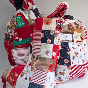May include: Two fabric Christmas gift sacks and a matching stocking made from patchwork fabric featuring reindeer, pudding, and striped patterns. One sack has a green patch with the text My First Christmas and a star tag labeled Harry.