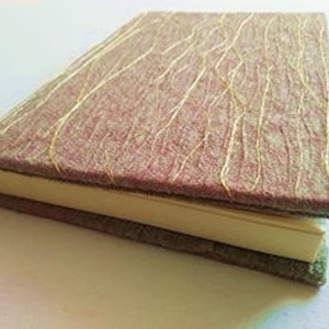 May include: A handmade journal with a purple fabric cover and gold thread accents. The journal has a spine and a ribbon bookmark.