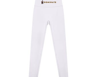 May include: Solid white high-waisted leggings featuring a small graphic of a person in a squatting position next to the gold-colored text "DOMINATE" printed on the center of the waistband. The leggings have a seamless design.